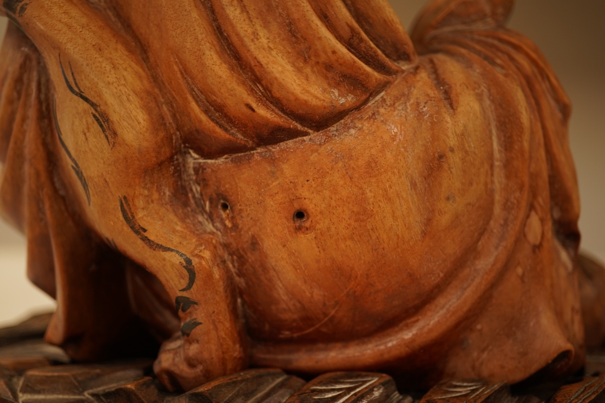 A Chinese hardwood carving of a seated luohan and tiger on hardwood stand, 24cm high including stand.